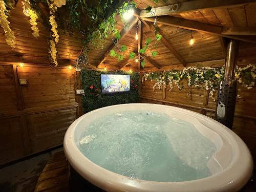 een badkamer met een bad en een tv. bij Dog Friendly Glamping Pods with Hot Tubs in Dwyran