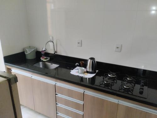 una cocina con encimera negra y fregadero en Apartamento 2 quartos en Pelotas