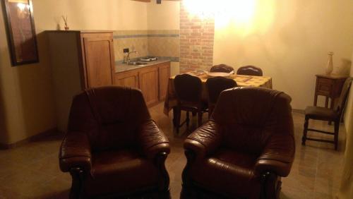 uma sala de estar com cadeiras de couro, uma mesa e uma cozinha em Agriturismo ErcolAna em Neviglie