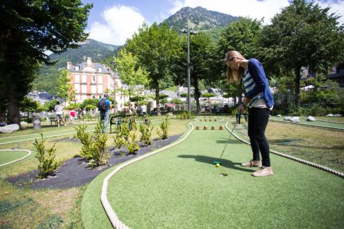 a woman playing a game of golf in a park at Hôtel Le Bois Joli in Cauterets