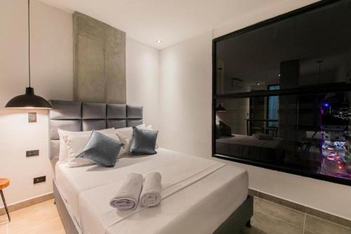 1 dormitorio con 1 cama grande y zapatillas. en Apartahotel Medellin en Medellín