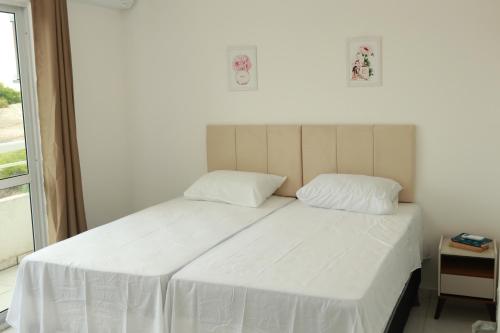 a white bed with two pillows in a bedroom at Apartamentos Cumbuco Condomínio Vila Real in Caucaia