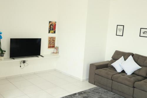 a living room with a couch and a flat screen tv at Apartamentos Cumbuco Condomínio Vila Real in Caucaia
