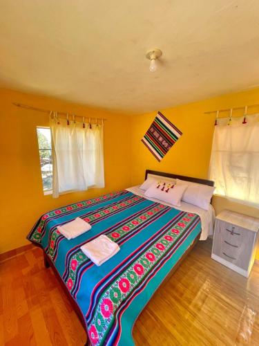 Arco Wasi Hospedaje Amantani في بونو: غرفة نوم مع سرير كبير مع بطانية ملونة