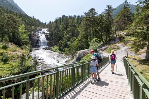 a group of people walking on a bridge over a river at Hôtel Le Bois Joli in Cauterets