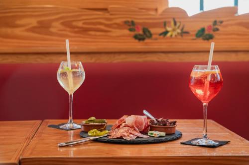 two glasses of wine and a plate of food on a table at Hôtel Le Bois Joli in Cauterets