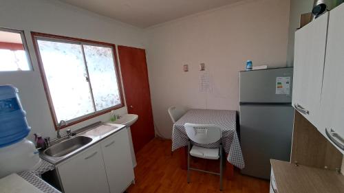 a small kitchen with a sink and a table and a refrigerator at Hostal Jardín del Desierto in Caldera