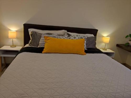 a bed with a yellow pillow and two lamps at Loft con Vista Panoramica Milenio lll Queretaro in Querétaro
