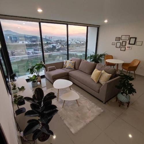a living room with a couch and tables and windows at Loft con Vista Panoramica Milenio lll Queretaro in Querétaro