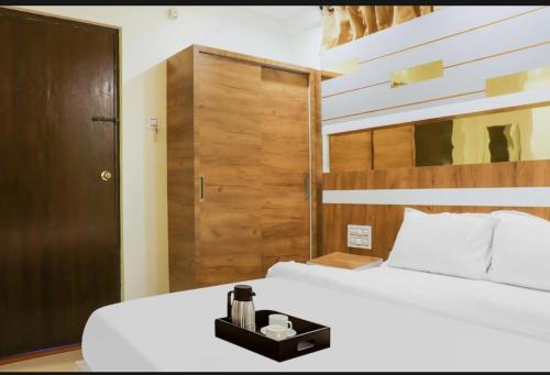 a bedroom with a white bed and a wooden door at Menaka in Vijayawāda