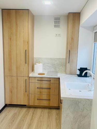 a kitchen with wooden cabinets and a sink at S&T&A&R apartamentai in Panevėžys