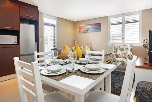 a dining room with a white table and chairs at Eden on The Bay 125 by HostAgents in Bloubergstrand