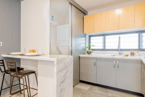 a kitchen with white cabinets and a bar with a chair at Tokio Loft Loft Moderno en Centro de Durango in Durango