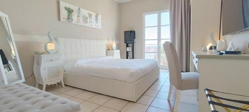 a white room with a bed and a table and a kitchen at Hotel Palladium in Monastir
