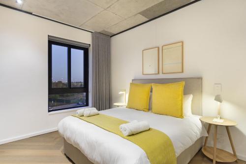 a bedroom with a large bed with yellow pillows at Bridgewater View 502 by HostAgents in Cape Town