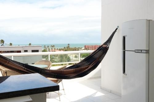a hammock on a balcony with a view of the ocean at Apartamentos Cumbuco Condomínio Vila Real in Caucaia