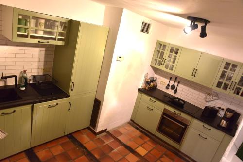 una cucina con armadi verdi e pavimento piastrellato di Gite Ardennes Au coin du feu jacuzzi sauna et nature a Jalhay