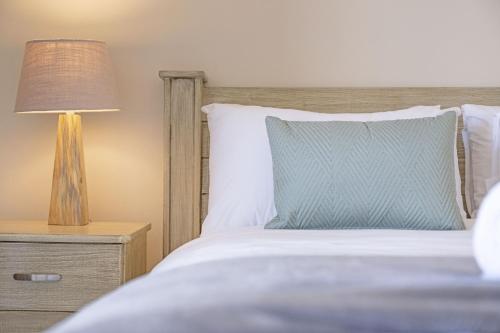 a bedroom with a bed and a lamp on a night stand at Portico 405 by Host Agents in Bloubergstrand