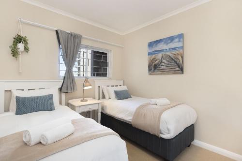 a bedroom with two beds and a window at Portico 405 by Host Agents in Bloubergstrand