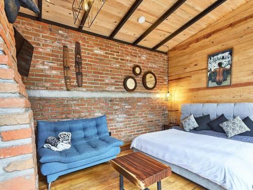 a bedroom with a bed and a couch and a brick wall at Cabaña Luna del Bosque in Tapalpa