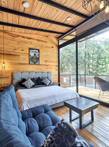 a bedroom with a large bed and a couch at Cabaña Luna del Bosque in Tapalpa