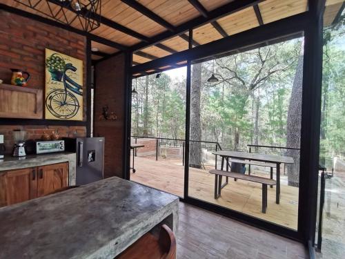 a kitchen with a table and a large sliding glass door at Cabaña Luna del Bosque in Tapalpa