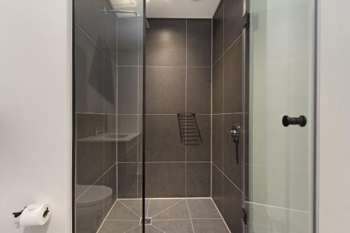 een badkamer met een douche en een glazen deur bij Bridgewater View 415 by HostAgents in Kaapstad
