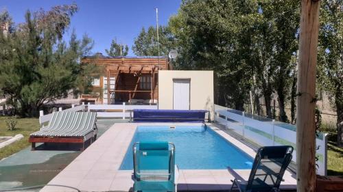 uma piscina com duas cadeiras e um banco em Cabaña La Escondida em Trelew