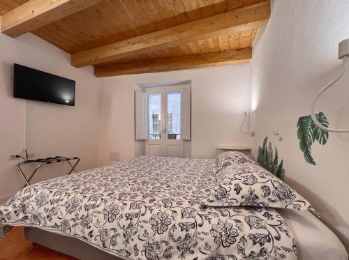 - une chambre avec un lit et une télévision murale dans l'établissement Al Duomo di Cagliari, à Cagliari