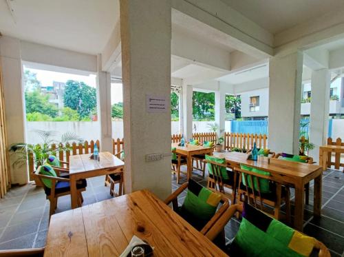um restaurante com mesas e cadeiras de madeira e janelas em Ornate Service Apartments em Pune