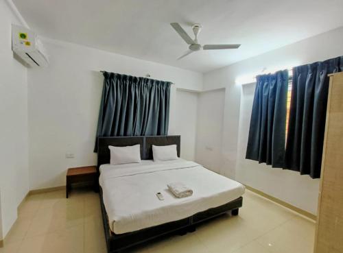 um quarto com uma cama branca e cortinas azuis em Ornate Service Apartments em Pune