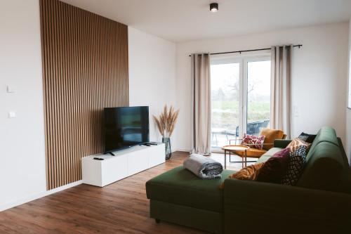 a living room with a green couch and a flat screen tv at Hunsrück Lodge in Mittelstrimmig