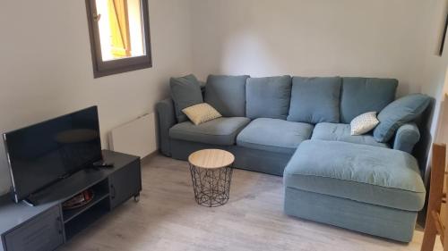 un salon avec un canapé bleu et une table dans l'établissement Bel appartement avec balcon, aux Angles