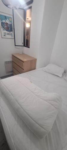 - une chambre avec un lit blanc, une commode et un miroir dans l'établissement Bel appartement avec balcon, aux Angles