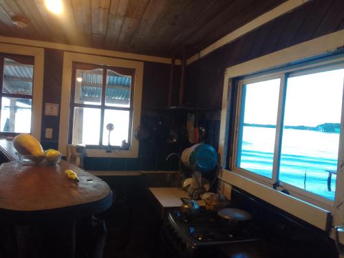 eine Küche mit 2 Fenstern, einem Tisch und einem Herd in der Unterkunft Casa elba sobre el mar in Bocas del Toro