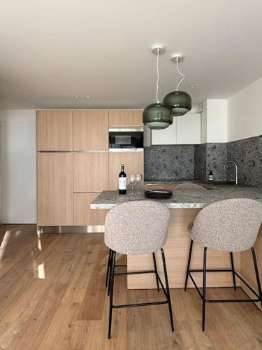 - une cuisine avec deux tabourets de bar et un îlot de cuisine dans l'établissement Appartement Les Hirondelles, à Aix-les-Bains