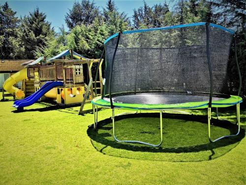 a playground with a trampoline in the grass at Country house with 2,500m of garden and playground in Jolalpan