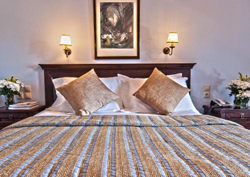 a bed with two pillows and a night stand at Hotel Doupiani House in Kalabaka