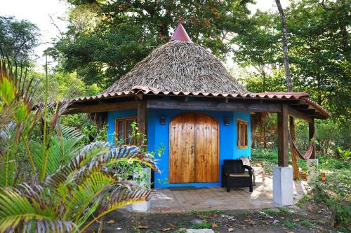 a small blue house with a thatch roof at Hotel Oasis & Surf Camp in Santa Catalina
