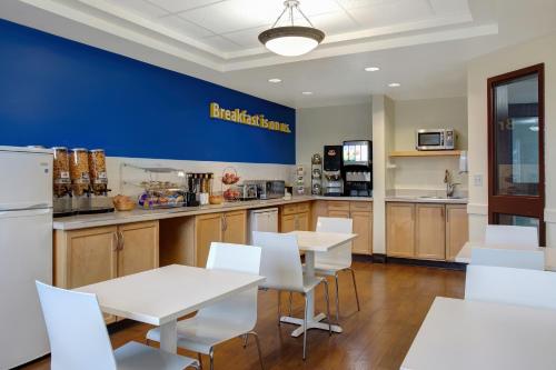 a kitchen with white tables and white chairs at Days Inn by Wyndham Whitecourt in Whitecourt