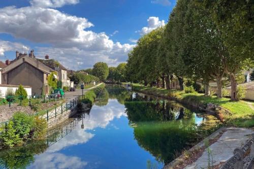 a river in a village with a blue sky and clouds at Appartement Cosy Nemours in Nemours