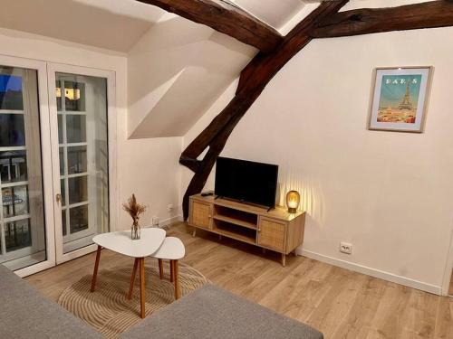 a living room with a tv and a table at Appartement Cosy Nemours in Nemours