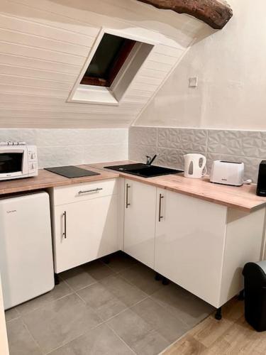 une cuisine avec des armoires blanches et un évier dans l'établissement Appartement Cosy Nemours, à Nemours
