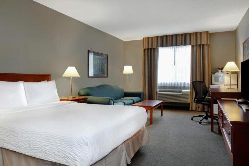 une chambre d'hôtel avec un lit, un canapé et un bureau dans l'établissement Days Inn by Wyndham Whitecourt, à Whitecourt