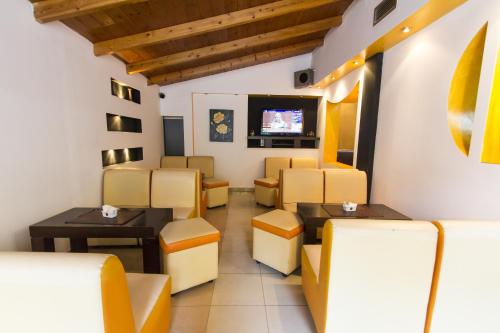 una sala de espera con sillas amarillas y TV de pantalla plana. en Vila 57 HOTEL, en Tirana