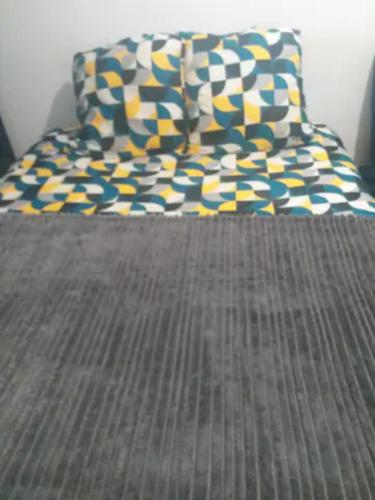 - un lit avec un oreiller jaune et bleu dans l'établissement 3 chambres à louer dans l'appartement deux pas à Tramway2, à Colombes