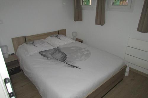 una camera da letto con letto, lenzuola e cuscini bianchi di Appartement T2 neuf Bages centre a Bages