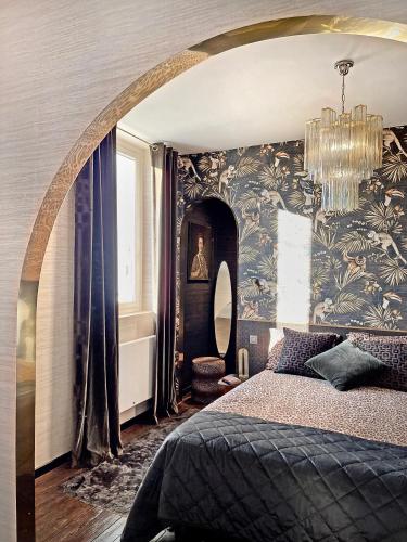une chambre avec un grand lit et un lustre dans l'établissement Les Alcoves - Studios design, à Villers-Cotterêts