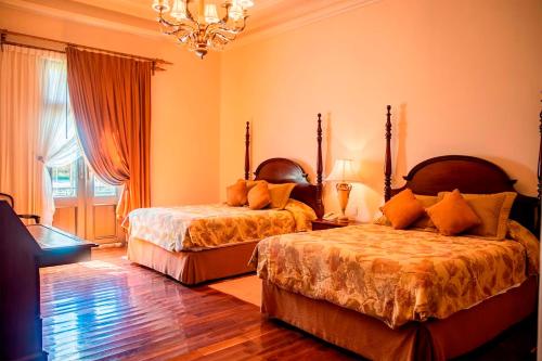 1 Schlafzimmer mit 2 Betten und einem Kronleuchter in der Unterkunft Real Hacienda Santo Tomás in El Hospital