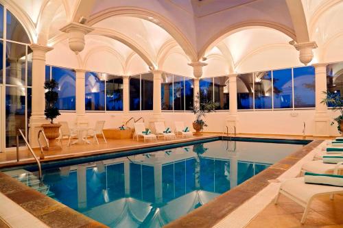 an indoor pool with chairs and a large room at Real Hacienda Santo Tomás in El Hospital
